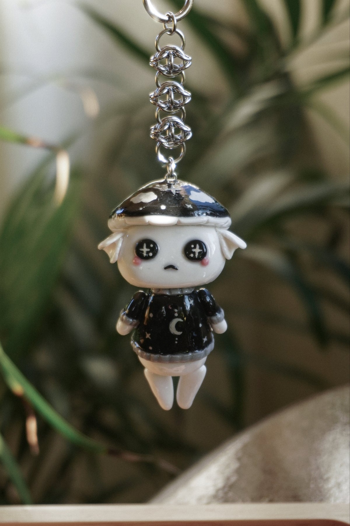 mushroom clay keychain with a black and gray celestial outfit
