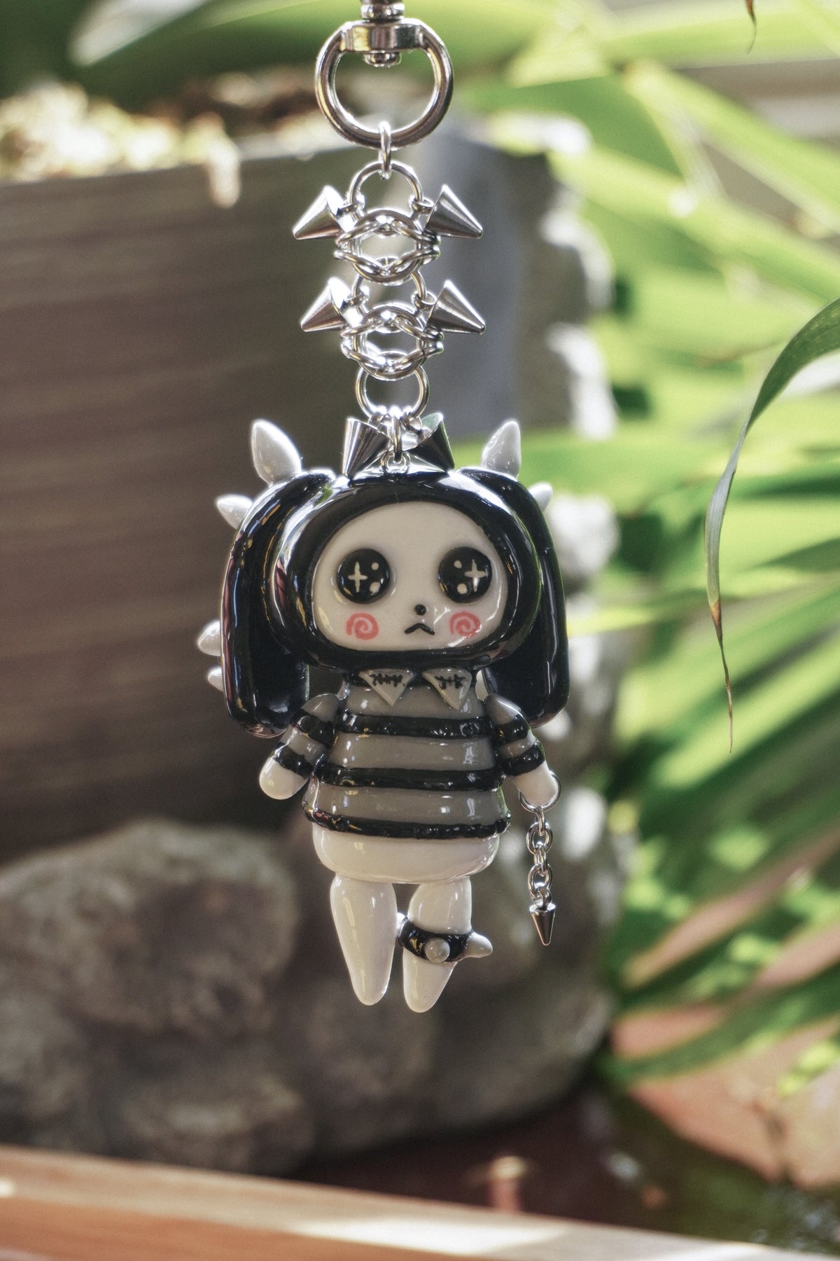 a bunny spirit clay keychain with spikes wearing a black and gray sweater